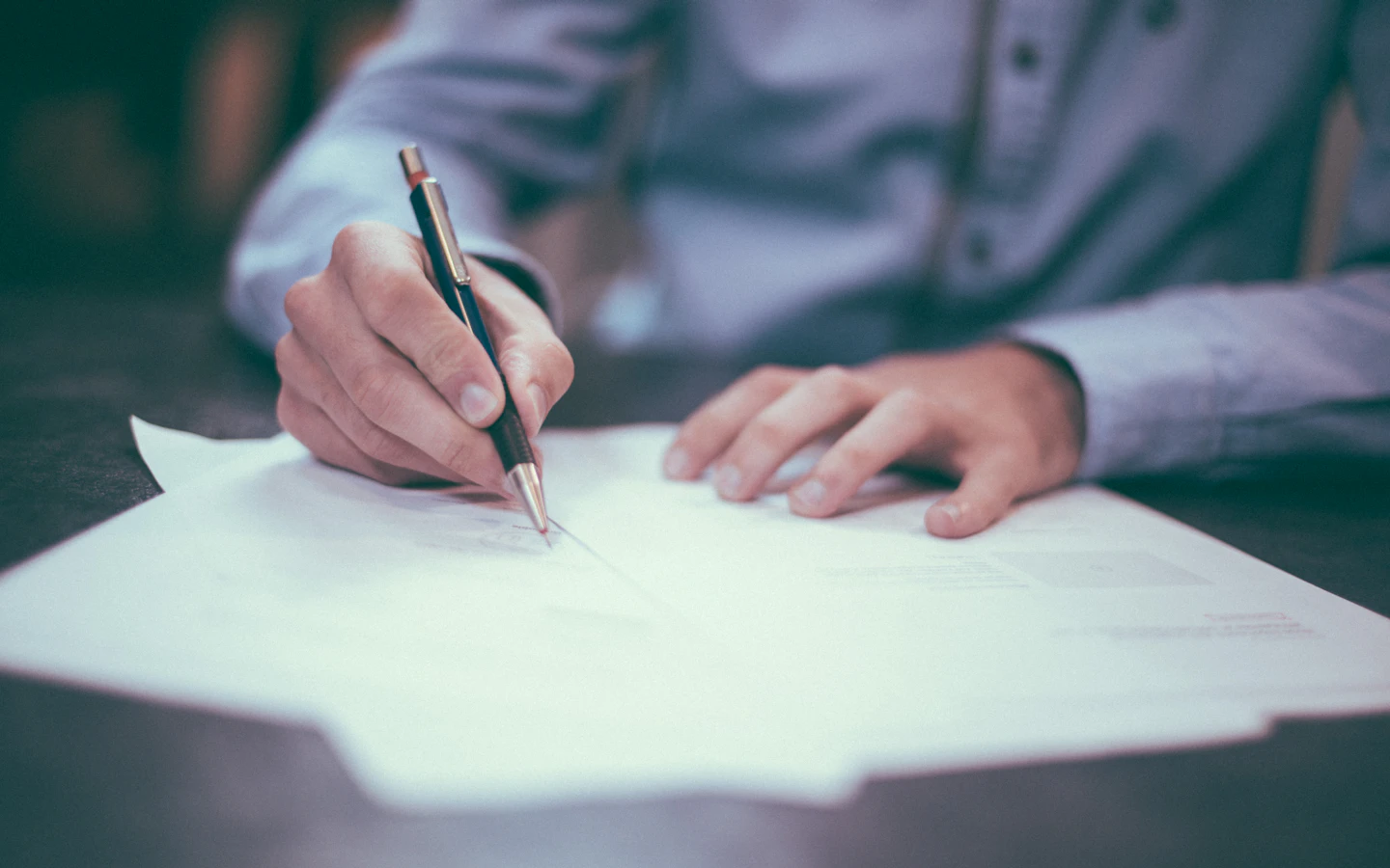 Persona firmando un contrato sobre el escritorio